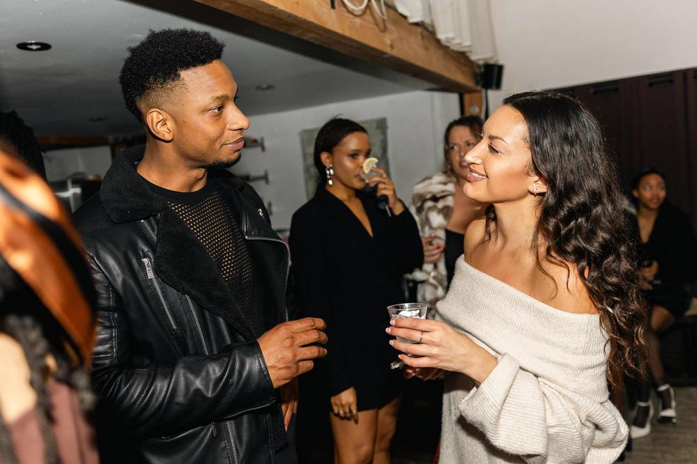 Two guests talking face to face at an evening event, drinks in hand
