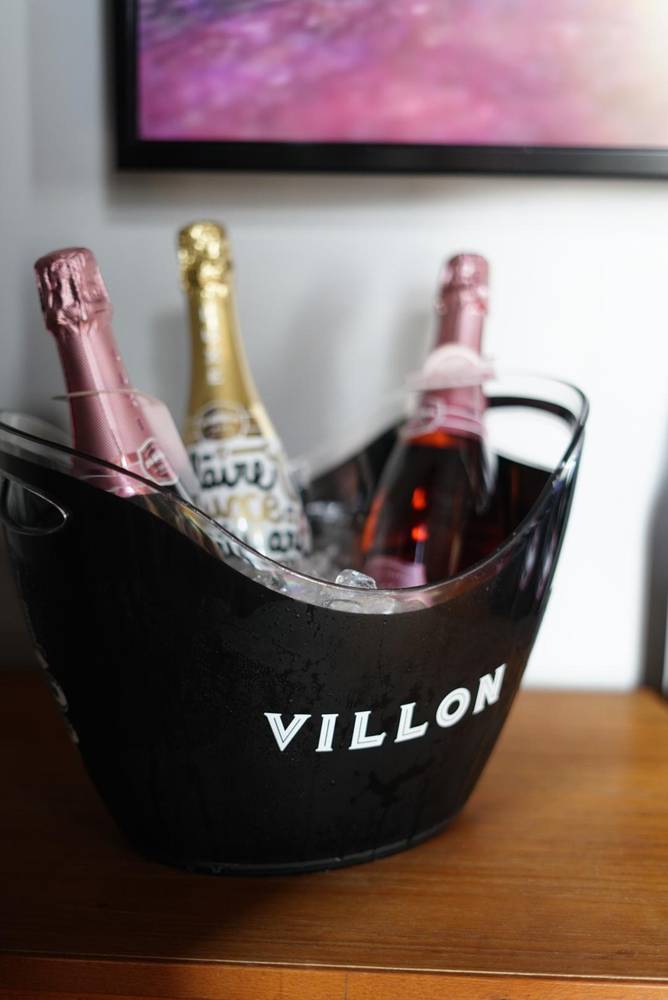 Champagne and rosé bottles chilling on ice in a black Villon bucket