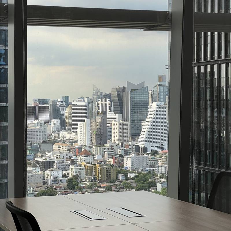 A bright office with a long table and a wide city view through tall windows